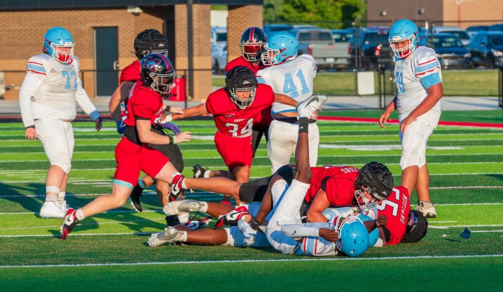 Mustang’s defense wraps up a Lawton Eisenhower ball carrier. Photo by Michael Kinney