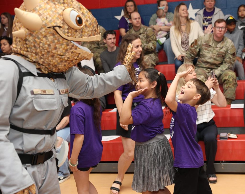 Students at Tinker Elementary give high fives to Tink, a mascot from Tinker Air Force Base, Friday, April 3 during a school assembly. The Mid-Del school was designated as a Purple Star School. Photo by Jeff Harrison